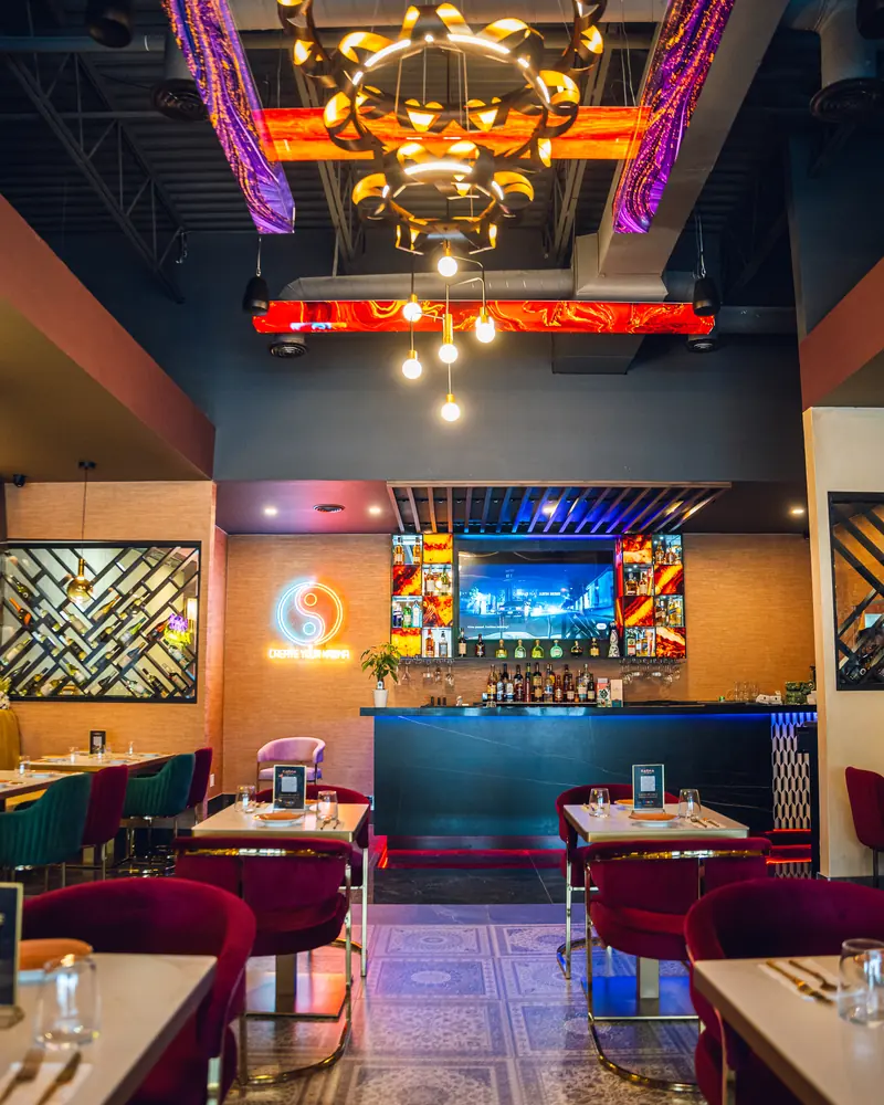 The dining room looking through to the bar, with the neon Karma emblem lit on the back wall