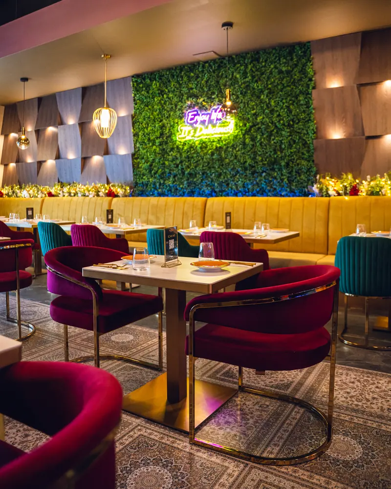 Velvet chairs and marble tables in front of the living green wall