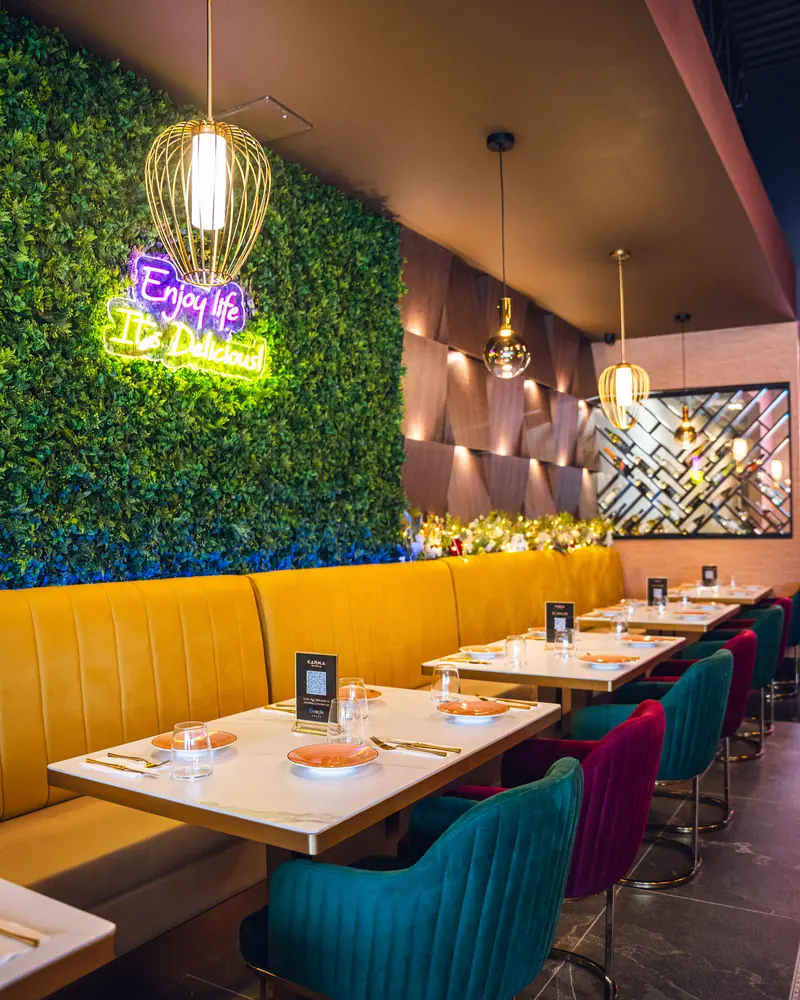 Tables laid along the banquette beneath the neon ‘Enjoy life, it’s delicious’ sign
