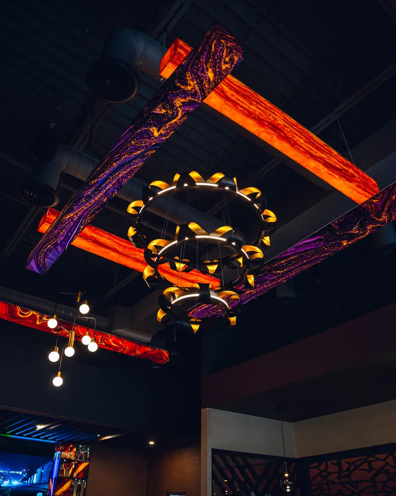 Sculptural brass and neon light fittings across the ceiling