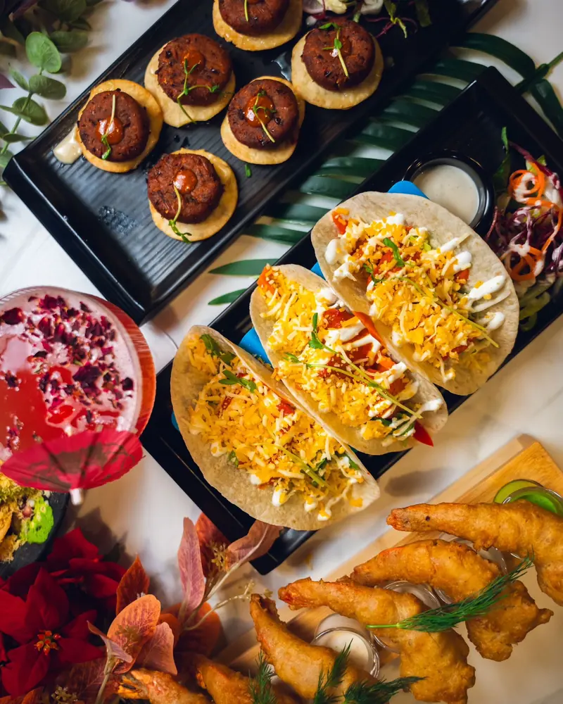 A sharing platter of Delhi street tacos, kebabs and a garnished cocktail