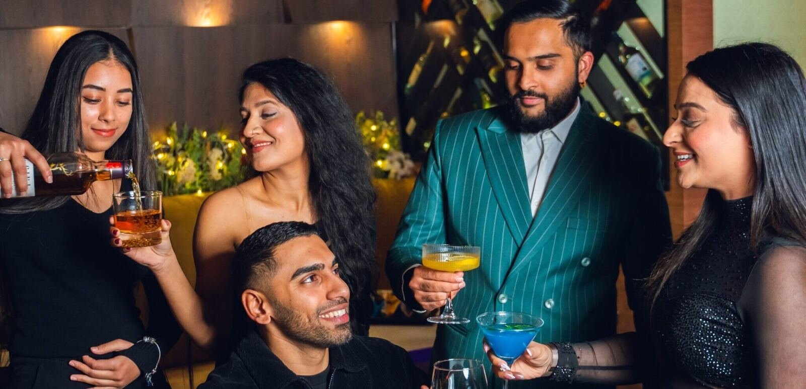 Friends raising cocktails together at a table in Karma