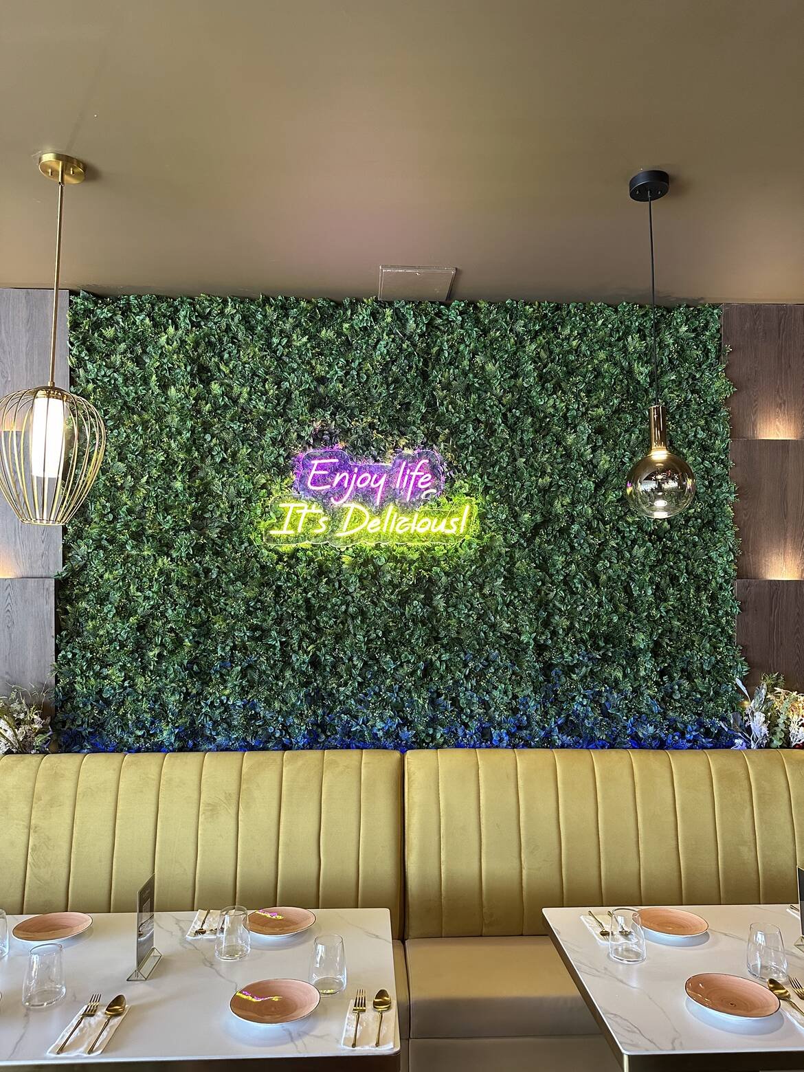 Banquette seating beneath a neon ‘Enjoy life, it’s delicious’ sign