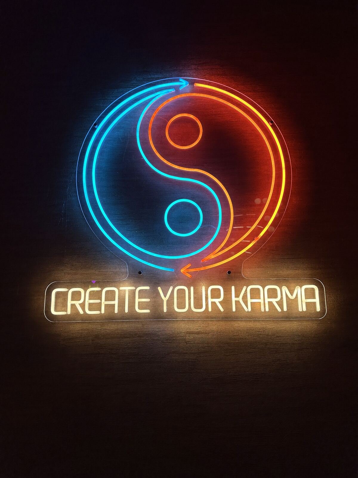 Neon ‘Create Your Karma’ sign glowing inside the Karma bistro dining room